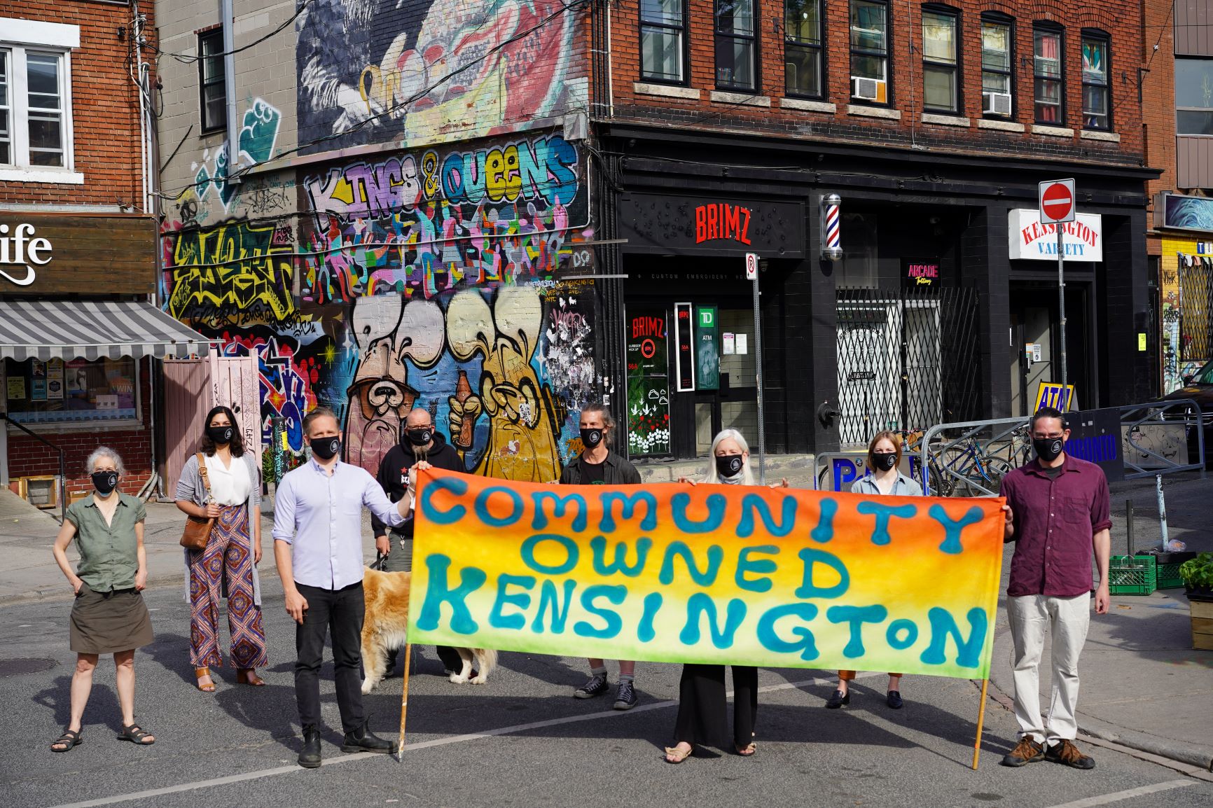 Protesters standing holding a banner that reads "Community Owned Kensington" 