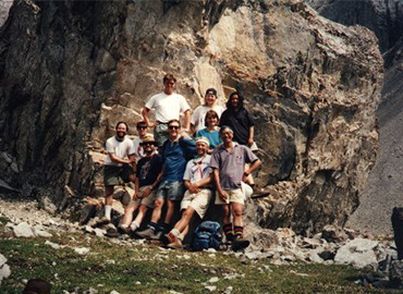 A research group standing in front of a large rock formation.