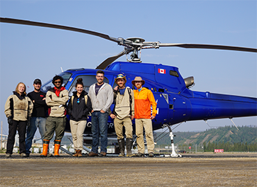 7 lab members standing in front of a helicopter.