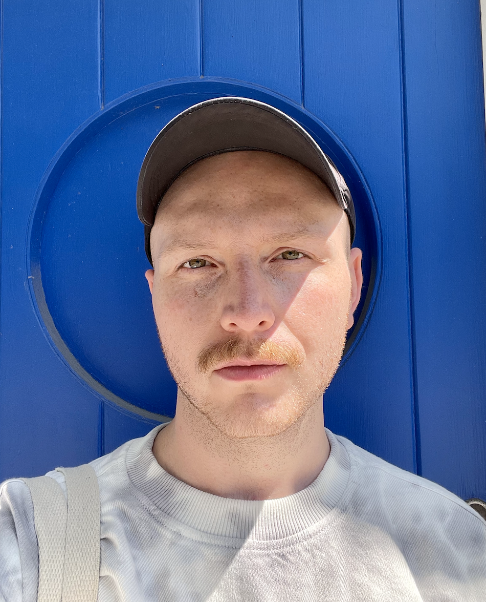 Travis in front of a blue wall.